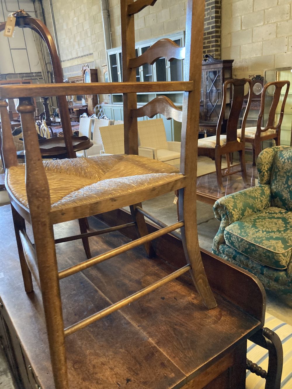 An Arts & Crafts ladder-back rush-seat elbow chair and an Edwardian inlaid mahogany three-tier cake stand (faults), 96cm high